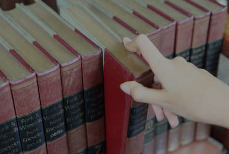 Jakarta, Indonesia-August 16, 2021: Close up of a hand taking an encyclopedia book from a bookshelf