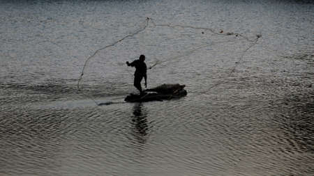 Jakarta, Indonesia-August 18, 2021: fisherman silhouette in the middle of the lakeのeditorial素材
