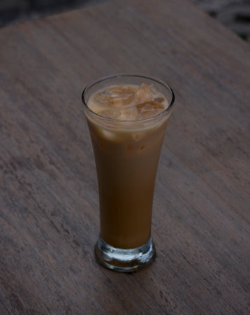 a glass of iced Thai tea on a wooden table