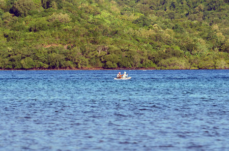 Fishermen in a boat on the background of green forest.