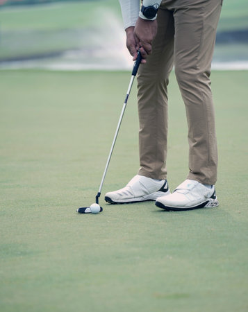 Golfer putting golf ball on the green of golf course.