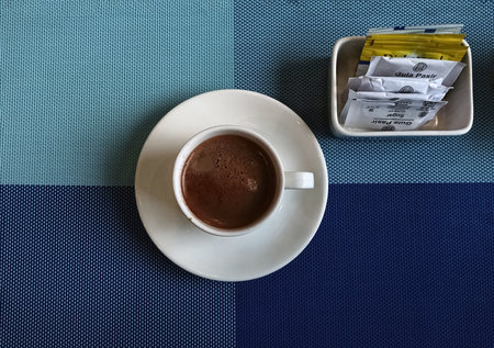 Cup of coffee and a saucer on a blue tableclothの写真素材