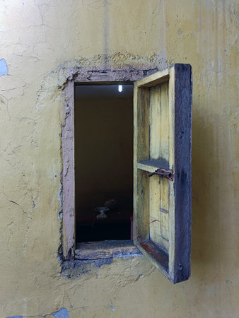 Old wooden window on a yellow wall in a house in the villageの写真素材