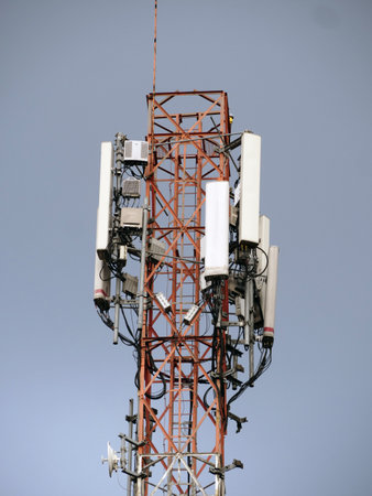 Telecommunication tower with antennas against blue sky, closeup of photo