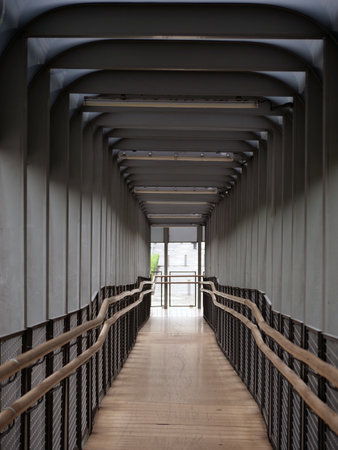 Wooden walkway with metal railings in a modern building.の写真素材