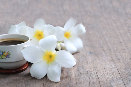 Plumeria flowers with black coffee on wooden blur backgroundの写真素材