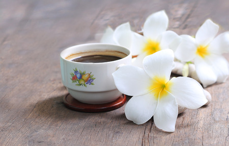 Plumeria flowers with black coffee on wooden blur backgroundの写真素材