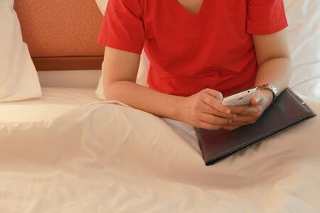 Women working with smartphones while sitting on the bed