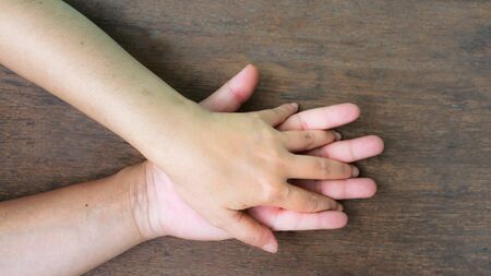 Hand together love family sign symbolizing help and hope wood background
