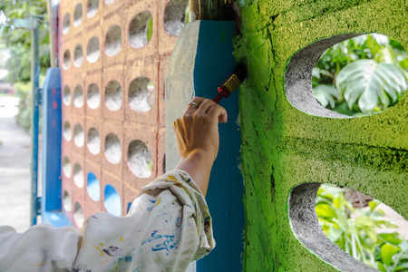 Close up of painter hand up painting a wall with paint brushの写真素材