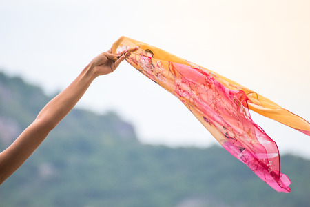 Beautiful young woman with flying scarf on beach,Carefree girl seaside holding scarf fluttering in the wind.の写真素材