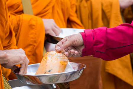 Buddhist monk of Thailand while stand in a row waiting people put rice and food offerings in their alms bowl for make meritの写真素材