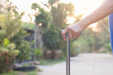 Asian old woman standing with his hands on a walking stick,Hand of old woman holding a staff caneの写真素材