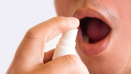 Man spay oral medications reduce cough on White Background,drugs or pills health care conceptの写真素材