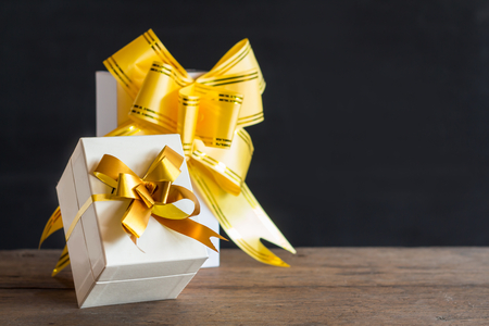 White gift box and yellow ribbon with tag on wood table with space,black backgroundの写真素材