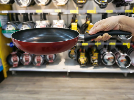 Asian woman shopping in supermarket store and checking her smartphone with pushing shopping cart,blur backgroundの写真素材
