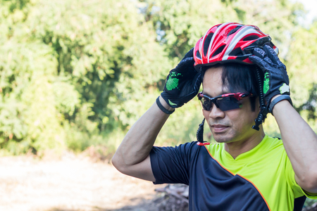 Man with helmet glove for safety riding a bicycle at countryside road along a forest,Cross country riding,cycling activity and sports.の写真素材