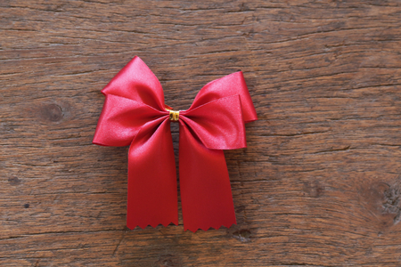 Red ribbon with bow on wooden backgroundの写真素材