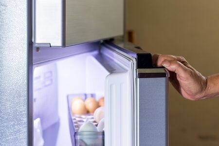 Abstract female hand of woman is opening a gray refrigerator doorの写真素材