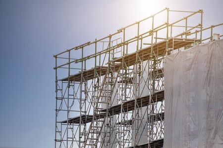 Construction site with scaffold tower and warning label building with sky background, scaffolding...