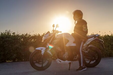 Asian woman with helmet and wearing and fasten before riding big bike motorcycle on the road for...