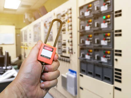 Hand holding red key lock and tag for process cut off electrical,the toggle tags number for electrical log out tag outの写真素材