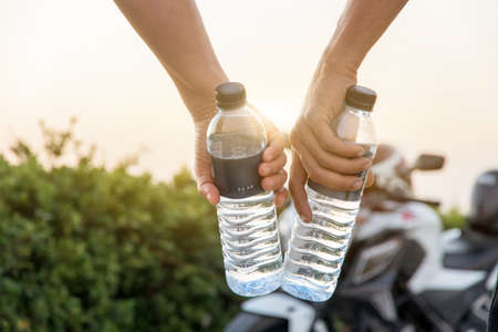Hand holding bottle water with big bike background,Summer holiday vacation outdoor and view in...