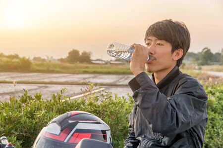 Hand holding bottle water with big bike background,Summer holiday vacation outdoor and view in...