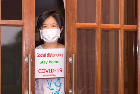Asian women wear surgical mask are holding paper label about disease virus covid-19 preventionの写真素材