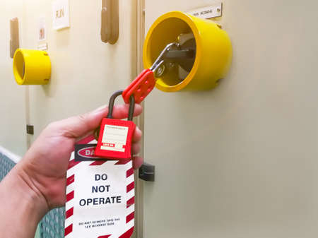 Hand holding red key lock and tag for process cut off electrical,the toggle tags number for electrical log out tag outの写真素材