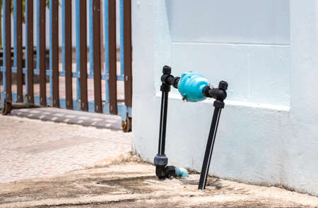 Blue water meter and valve supply pipe with joint and hold on front side home cement wall,plumbing...