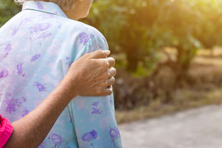 Asian old woman standing with her hands on a walker with daughter's hand,Hand of old woman holding a...