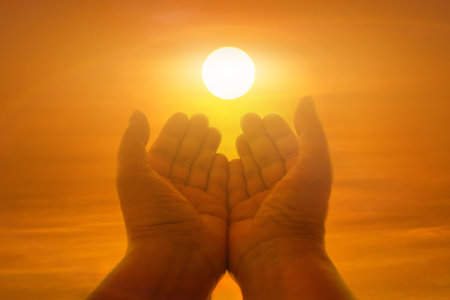 Silhouette of female hands holding lights of setting sun during sunset