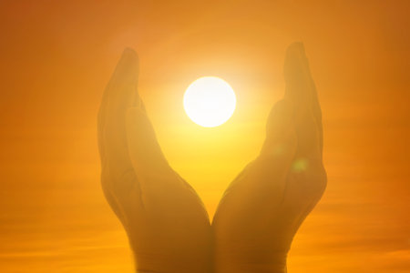 Silhouette of female hands holding lights of setting sun during sunsetの写真素材