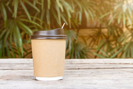 Paper cup with a lid for coffee to go on wood table,Coffee take away is on the table nature blackground,There is space for text in the backgroundの写真素材