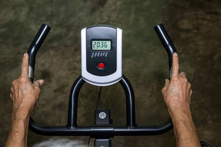 Hand of Elderly or Senior woman exercise on spinning bicycle at home