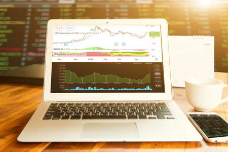 Laptop show stock chart for business and coffee with nature background, outdoor officeの写真素材