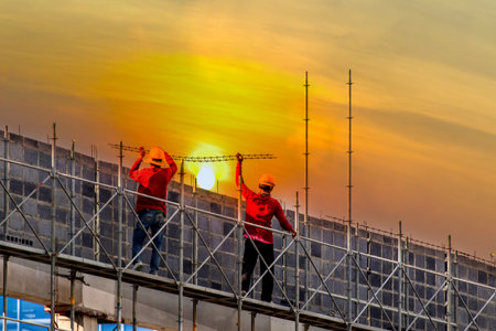 Man working on construction site with scaffold and building with sun set background,scaffolding for construction factoryの写真素材