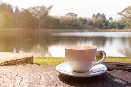 A white cup of hot espresso coffee mugs placed on a wooden floor and natural pool with sunlight background,coffee morningの写真素材