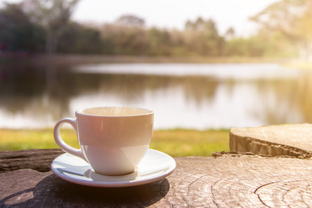 A white cup of hot espresso coffee mugs placed on a wooden floor and natural pool with sunlight background,coffee morningの写真素材