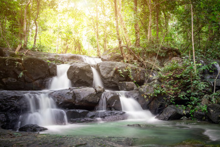 Small waterfall with water splashing and tumbling over the rocks in the forest on a bright sunnyの写真素材