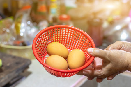 Chicken eggs in a woman's hand. Housewife is preparing eggs for cooking in the kitchen.の写真素材