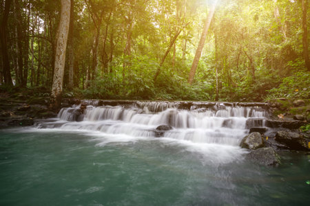 Small waterfall with water splashing and tumbling over the rocks in the forest on a bright sunnyの写真素材