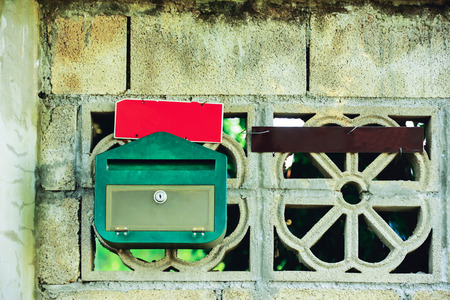 Postbox red and green plastic sheets are installed in the wall of cement.の写真素材