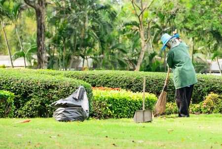 The gardener is cleaning the lawn full of fallen leaves.のeditorial素材