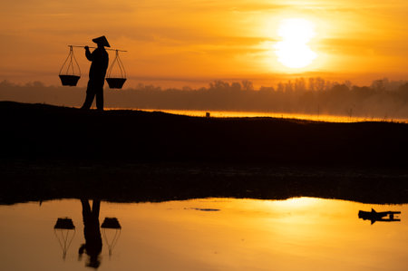 Thai farmers are carrying baskets to prepare to go home before the sun goes down. Silhouette farmer. Silhouette light.の写真素材