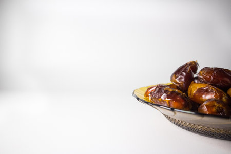 dried dates palm fruits on plate isolated on white  background. Popular during Ramadanの写真素材
