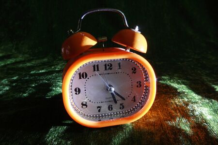 orange alarm clock on velvet fabricの写真素材
