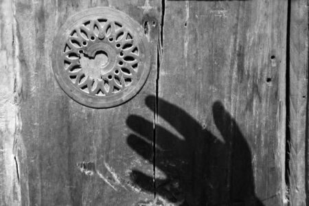 shadow of hand over old wooden doorの写真素材
