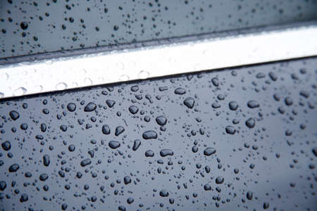 Water drops collect on top of metallic car surface